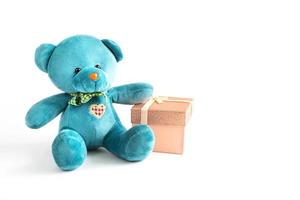 Türkisfarbener weicher Teddybär mit gesticktem Herzen hält eine Geschenkbox und eine Schleife auf weißem Hintergrund. Kinderspielzeug. liebe, ein geschenk zum urlaub, eine liebeserklärung, valentinstag. Platz kopieren foto