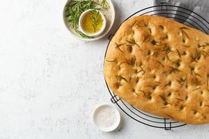 Focaccia, Pizza, italienisches Fladenbrot mit Rosmarin und Olivenöl auf dem Gitter foto