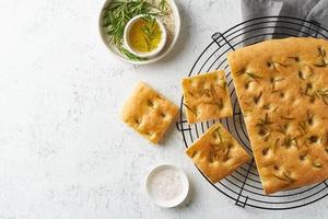 Focaccia, Pizza, italienisches Fladenbrot mit Rosmarin und Olivenöl auf dem Gitter foto