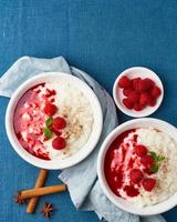 Reispudding. Französisches Milchdessert mit Himbeeren. blaues Textil. draufsicht, vertikal, kopierraum foto