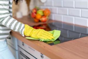 Horizontal von gesichtslosen, kurz geschnittenen weiblichen Waschinduktionskochfeldern in gelben Handschuhen mit grünem Waschlappen foto