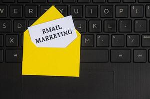 Draufsicht auf E-Mail-Marketing-Text auf Notizblock in einem Umschlag mit Laptop-Hintergrund. foto