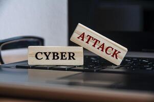 Cyber-Angriffstext auf Holzblöcken auf einem Laptop. foto