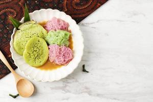 Pethulo, Srabi und Putu Mayang, serviert mit Kokosmilch-Palmzuckersirup, traditionelles indonesisches Dessert aus Ost-Java. auf weißem Tisch foto