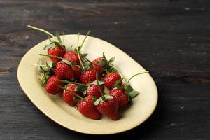 Erdbeere auf Sahneteller, Holztisch. foto