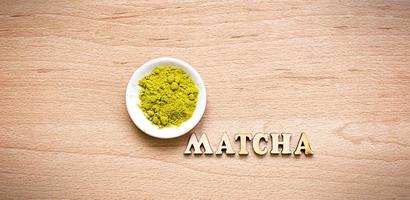 Japanischer Matcha-Tee aus grünem Pulver auf einer Platte, auf braunem Hintergrund. beschriftung der holzbuchstaben in englisch. loses Pulver. Platz für Text. Kochen, eine Zutat für ein belebendes Getränk foto