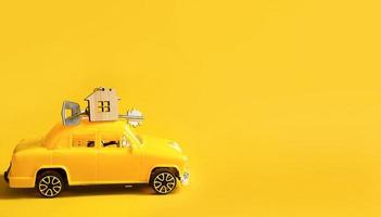 Gelbes Spielzeugauto mit Schlüssel zum Haus auf dem Dach auf farbigem Hintergrund. Umzug in ein neues Zuhause, Hypothek, Wohnungskauf, Taxi. Platz kopieren. foto