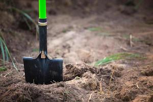 Schaufel wird in den Boden gesteckt, um im Frühjahr zu pflanzen. Frühling, Gartenpflanzen, Arbeiten auf einem Grundstück, Landschaftsgestaltung, Gärtnern, Blumen züchten, Obstkulturen im Garten. Platz kopieren foto