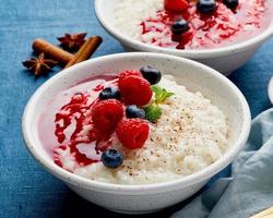 Reispudding. Französisches Milchreisdessert mit Himbeeren, Heidelbeeren. dunkler hintergrund, seitenansicht foto