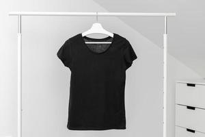 T-Shirt hängt am Kleiderständer. Rundhalsausschnitt in schwarzer Farbe. Vorlage, Mockup