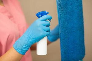 Person, eine Hand in einem blauen Gummihandschuh auf dem Bild, entfernt und wäscht das Waschbecken im Badezimmer foto