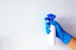 Person, eine Hand in einem blauen Gummihandschuh auf dem Bild, entfernt und wäscht das Waschbecken im Badezimmer
