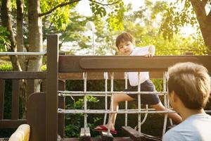 Glücklicher asiatischer kleiner Junge spielt gerne und geht im Park spazieren, mit Papa aus nächster Nähe, asiatischer Junge hat ein schönes Lächeln, während er seinen Vater ansieht. Porträt des kleinen Jungen im Park und auf dem Spielplatz. foto