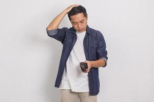 trauriger und verwirrter asiatischer mann, wenn er seine leere brieftasche sieht foto