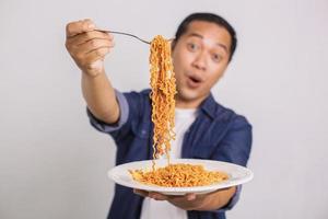 asiatischer Mann, der Instant-Nudeln isst und überrascht ist, wie lecker es ist foto