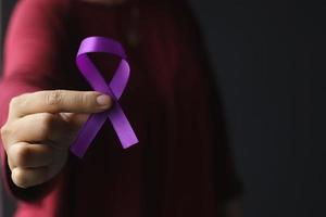 Hand mit lila Schleife für Alzheimer-Krankheit, Bauchspeicheldrüsenkrebs, Bewusstsein für Epilepsie, Weltkrebstag foto