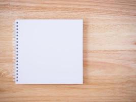 Notizbuch mit weißer Abdeckung auf braunem hölzernem Schreibtischhintergrund foto