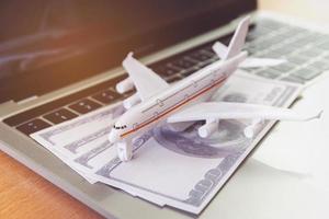Laptop-Computer und Flugzeug und Geld auf dem Tisch. Online-Ticket-Buchungskonzept foto