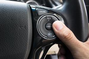 Hand drückt Tempomatknöpfe auf modernes Auto und Geschwindigkeitsbegrenzung foto