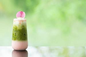 köstlicher saftiger grüner Tee der frischen Milch auf Glastisch verschwommenem Blattreflexionshintergrund foto