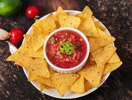 mexikanische Nacho-Chips und Salsa-Dip in Schüssel auf Holzhintergrund foto