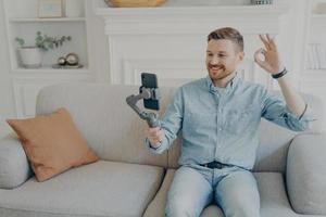 Junger Mann, der beim Video-Chat Daumen nach oben zeigt foto