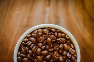 Kaffeebohnen in der Tasse auf grunge Holzhintergrund