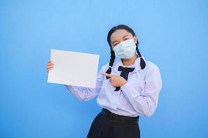 Schulmädchen zeigen Plakatwand auf blauem Hintergrund. foto