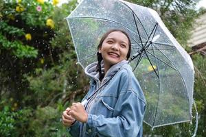 Lächeln Sie junges Mädchen, das Spaß im Regen hat. foto