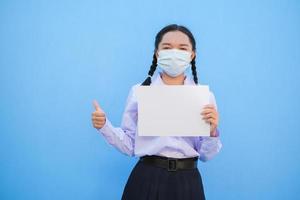 Schulmädchen zeigen Plakatwand auf blauem Hintergrund. foto