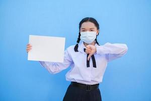 Schulmädchen zeigen Plakatwand auf blauem Hintergrund. foto