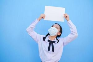 Schulmädchen zeigen Plakatwand auf blauem Hintergrund. foto