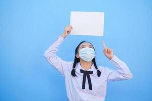 Schulmädchen zeigen Plakatwand auf blauem Hintergrund. foto