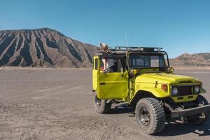 touristische frau, die auf tür steht, gelbes vierradauto in der wüste foto