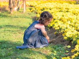 das mädchen sitzt im gras und betrachtet mit einer lupe die blumen auf dem feld foto