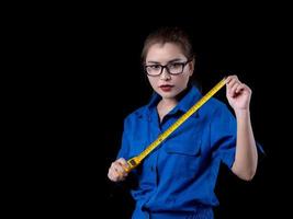 eine schöne frau in der blauen technikeruniform, die ein bauwerkzeug hält foto