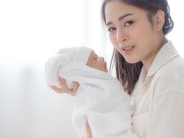 eine schöne asiatische frau trug ihr neugeborenes baby mit glück foto