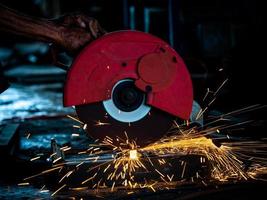 Professionelle Techniker in der Fabrik verwenden Elektrowerkzeuge, um das Metall zu schneiden foto