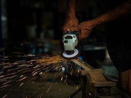 Professionelle Techniker in der Fabrik verwenden Elektrowerkzeuge, um das Metall zu polieren foto