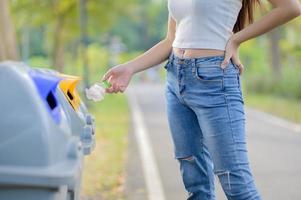 Eine Frau brachte die entleerte Plastikwasserflasche, sortiert in vorbereitete Behälter zur Aufbewahrung für das Recycling foto