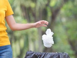 Die Frau warf eine Plastiktüte nach Gebrauch in den vorbereiteten Müll zur Aufbewahrung für das Recycling foto