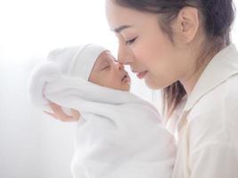 eine schöne asiatische frau trug ihr neugeborenes baby mit glück foto