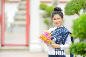 attraktive thailändische frau in einem alten thailändischen kleid hält frische blumen, die buddha huldigen, um sich auf dem traditionellen songkran-fest in thailand etwas zu wünschen foto