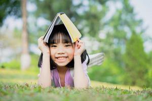 Bild des asiatischen kleinen Mädchens, das im Park studiert foto