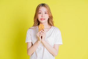 Bild eines jungen asiatischen Mädchens, das Hähnchen isst, das auf gelbem Hintergrund gebraten wird foto
