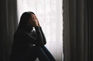 Frau sitzt Depression am Fenster und Angst foto