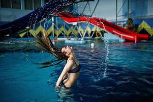 Porträt einer wunderschönen Frau im Bikini, die mit ihren Haaren im Pool im Wasserpark für Furore sorgt. foto