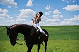 junges hübsches mädchen, das an einem sonnigen tag auf einem feld reitet. foto