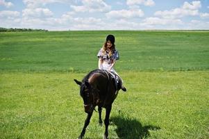 junges hübsches mädchen, das an einem sonnigen tag auf einem feld reitet. foto