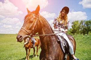 Schleppen Sie junge hübsche Mädchen, die an sonnigen Tagen auf einem Feld reiten foto